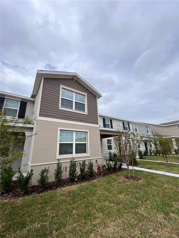 A two-story townhouse exterior features tan stucco, brown siding, and a small front garden — 10660 WORDS DRIVE, WINTER GARDEN, FL