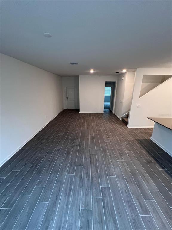 An open-concept living area features gray wood-look tile flooring, white walls, and a staircase — 10660 WORDS DRIVE, WINTER GARDEN, FL