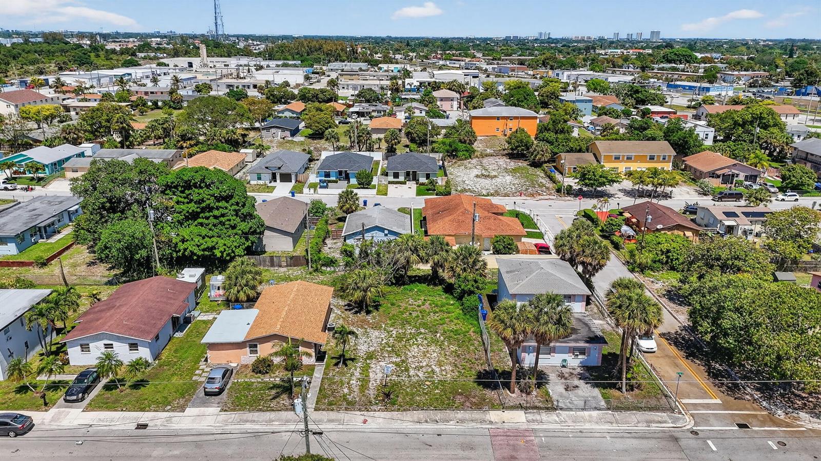 An aerial view shows a residential neighborhood with several houses and a vacant lot — 1204 W 35th Street, Riviera Beach FL 33404, RIVIERA BEACH, FL