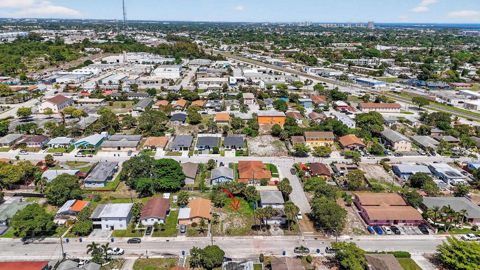 An aerial view shows a vacant residential lot situated between two houses on a street — 1204 W 35th Street, Riviera Beach FL 33404, RIVIERA BEACH, FL