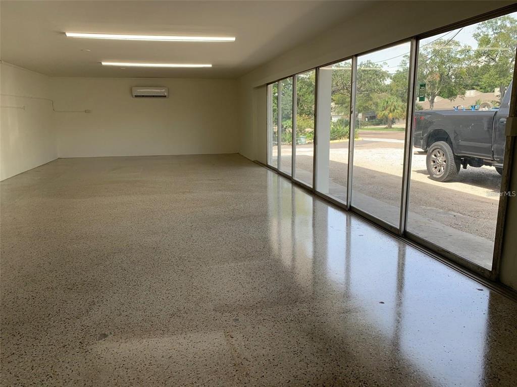 A large, empty room with polished concrete floors, recessed lighting, and floor-to-ceiling glass windows — 1100 S MYRTLE AVENUE, CLEARWATER, FL