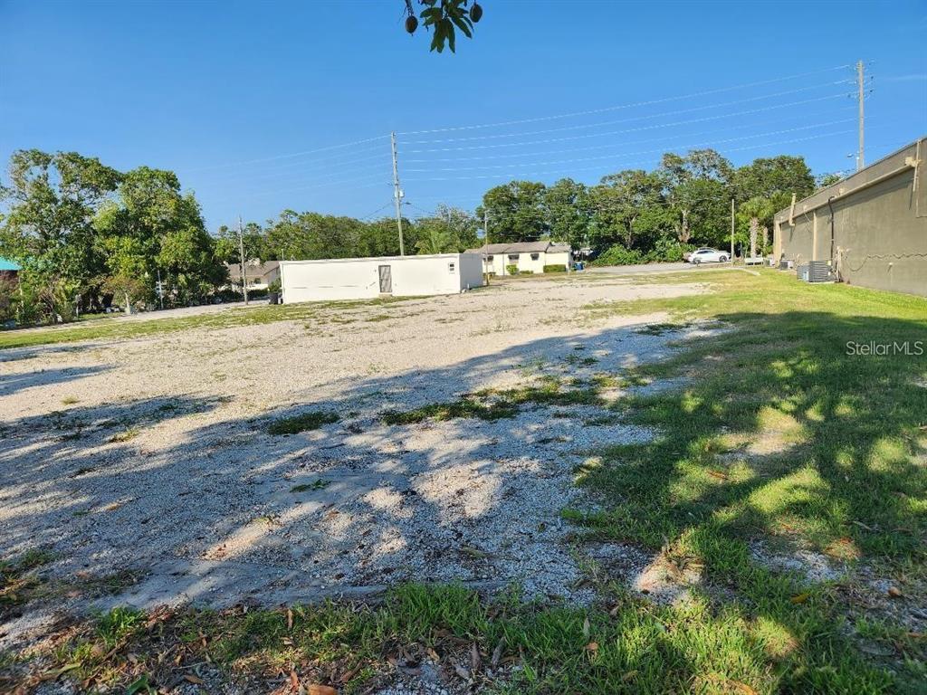 A large, flat, gravel-covered vacant lot sits adjacent to a building and trees — 1100 S MYRTLE AVENUE, CLEARWATER, FL