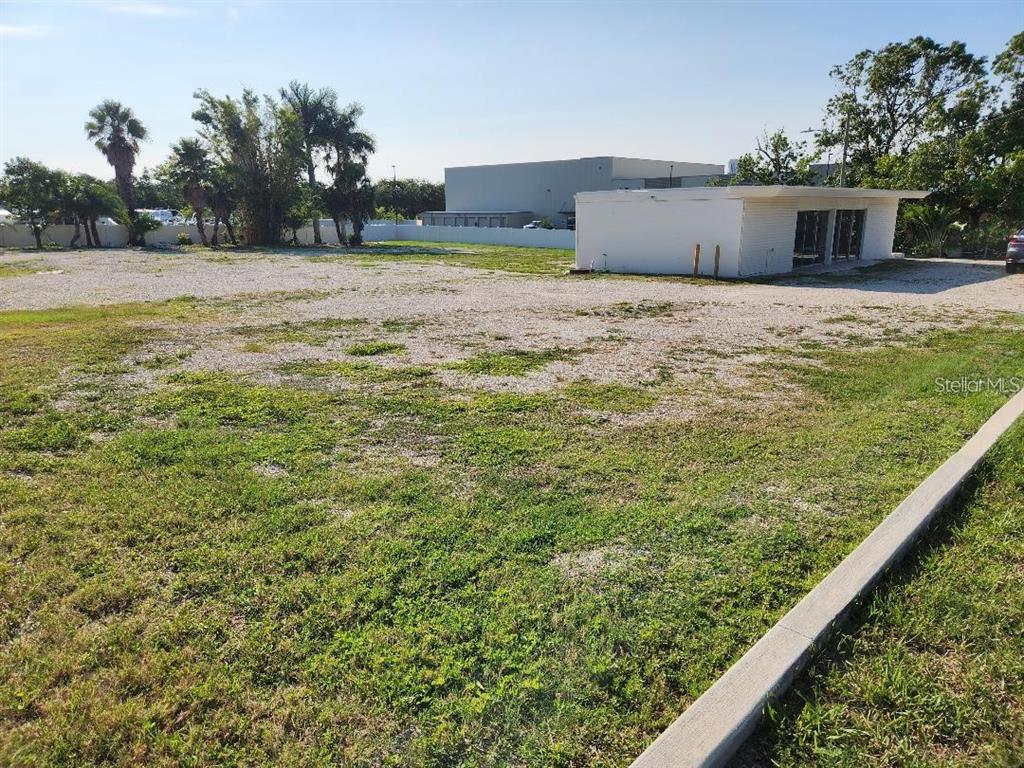 A large, flat, gravel-covered lot features a small, white, single-story building on the right — 1100 S MYRTLE AVENUE, CLEARWATER, FL