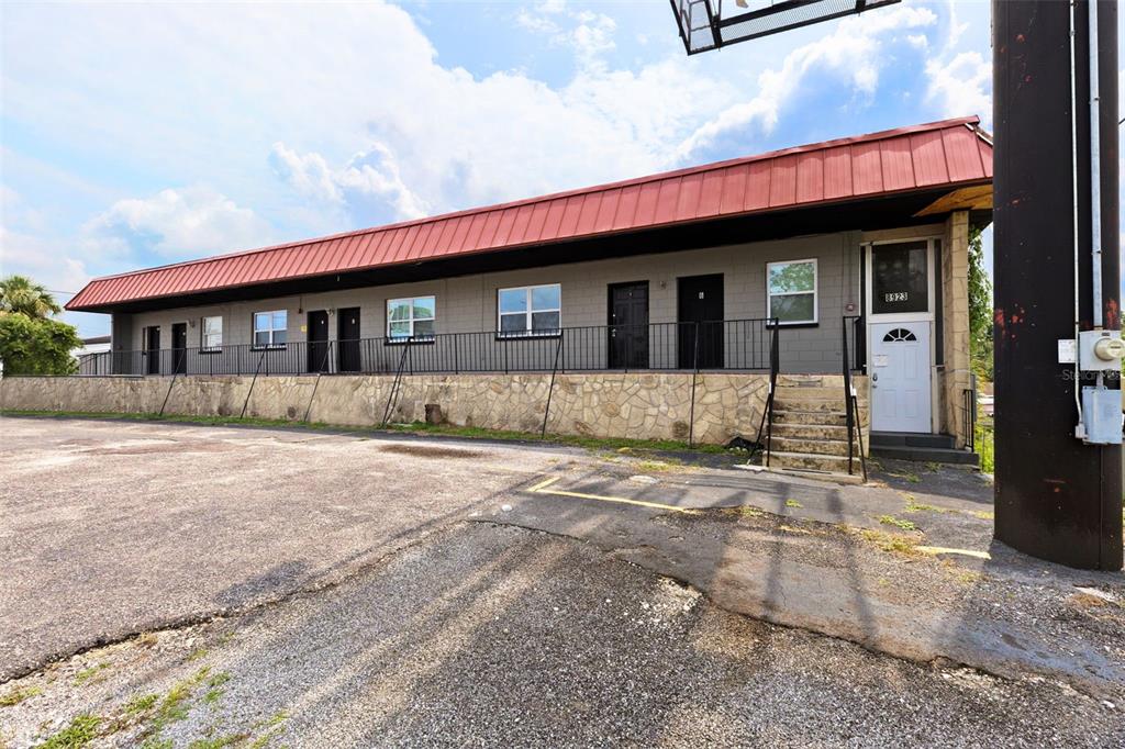 A single-story commercial building with a red metal roof, stone foundation, and exterior entry doors — 8923 N 40TH STREET, TAMPA, FL