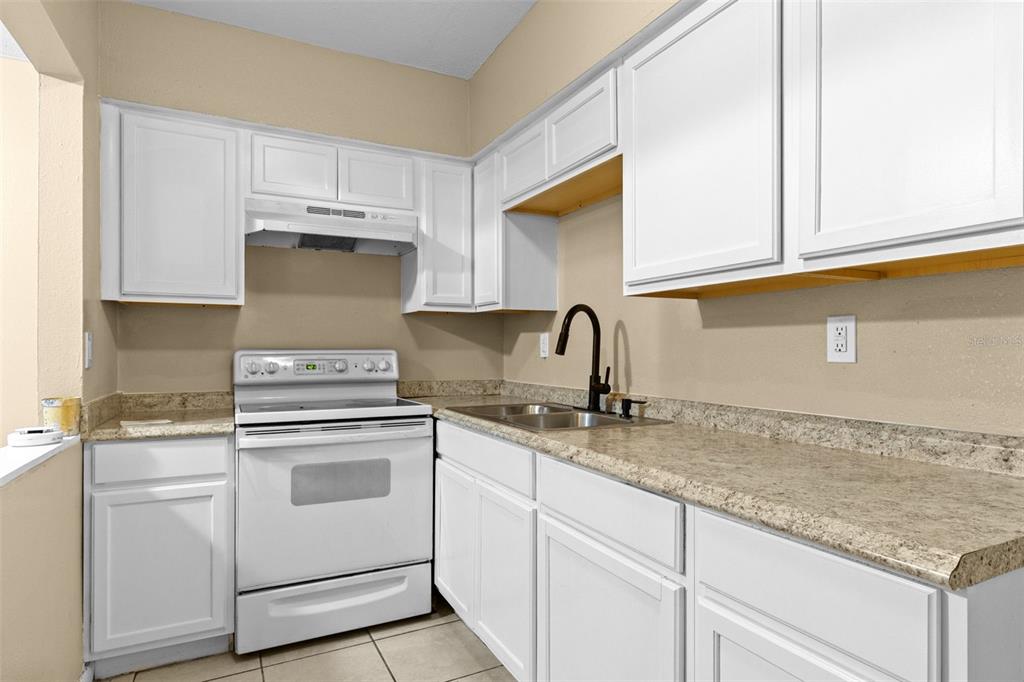 A kitchen with white cabinets, a white stove, and speckled laminate countertops — 8923 N 40TH STREET, TAMPA, FL