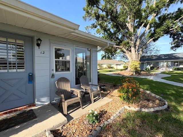 A light blue exterior wall features a front door, two chairs, and a landscaped garden — 1902 DANDRIDGE STREET UNIT 12, SUN CITY CENTER, FL