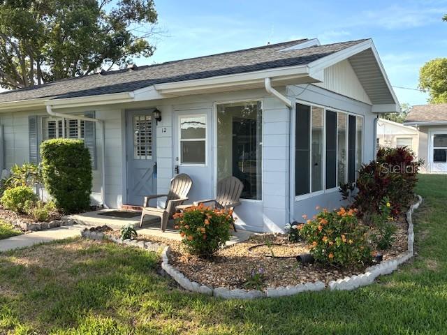 A light blue house with a covered porch, two chairs, and a landscaped garden bed — 1902 DANDRIDGE STREET UNIT 12, SUN CITY CENTER, FL