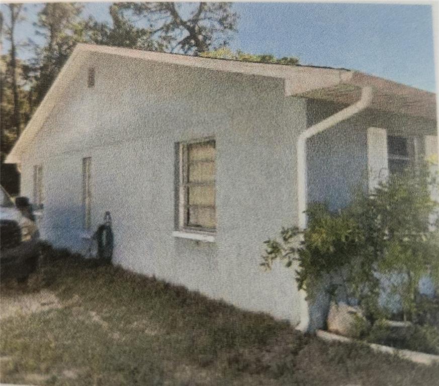 The exterior side view of a white, single-story house with a gabled roof and windows — 11234 ELGIN BOULEVARD, SPRING HILL, FL