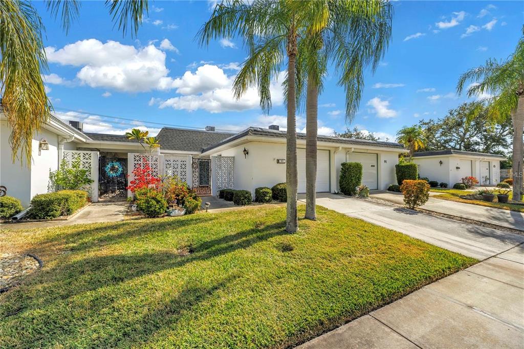 A single-story white house with a two-car garage, palm trees, and a landscaped front yard — 93 BOCA CIEGA POINT BOULEVARD N UNIT 93, ST PETERSBURG, FL