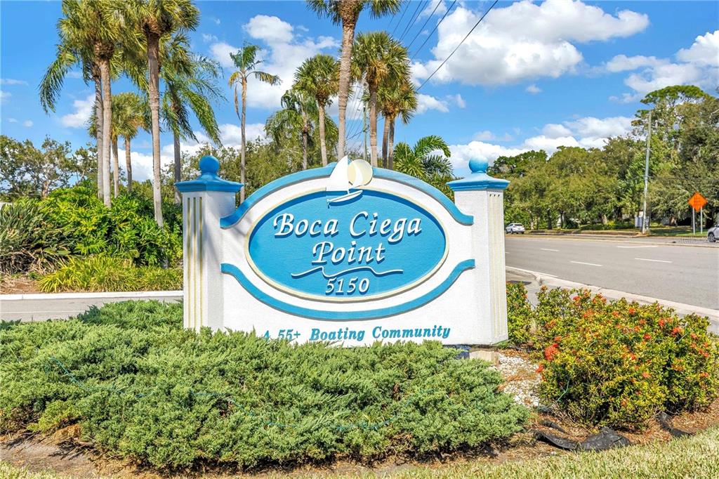 A blue and white community sign stands in front of palm trees and landscaping — 93 BOCA CIEGA POINT BOULEVARD N UNIT 93, ST PETERSBURG, FL