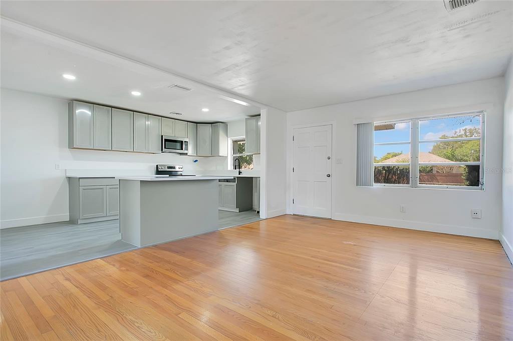 A kitchen with grey cabinets and a peninsula opens into a living area with hardwood floors — 1951 S CRYSTAL LAKE DRIVE, ORLANDO, FL