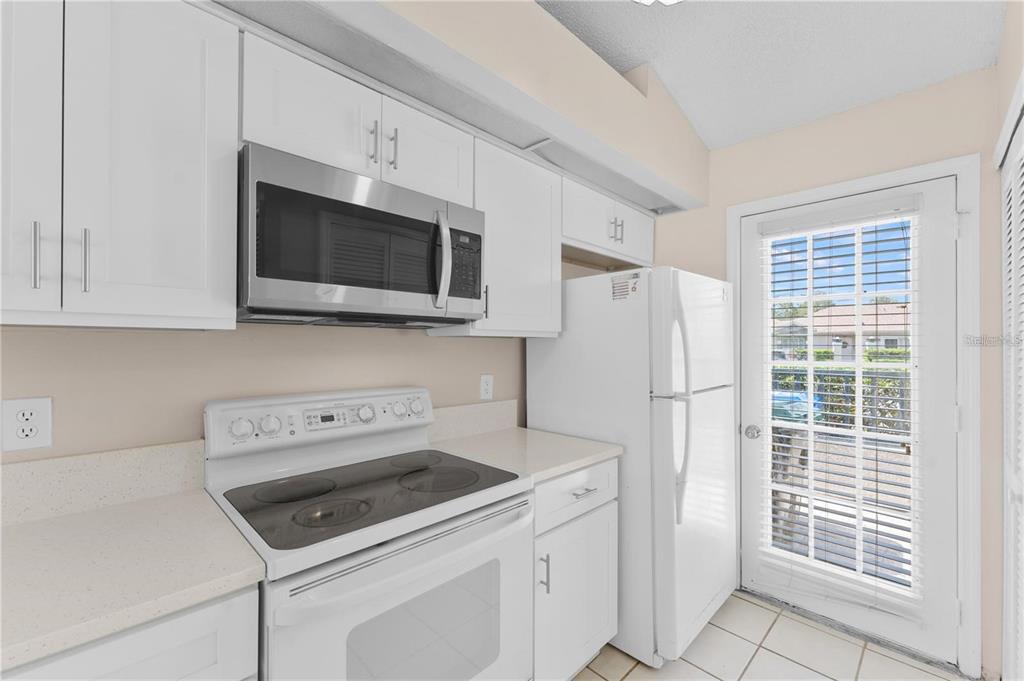 A kitchen features white cabinets, a stainless steel microwave, a white stove, and a glass door — 1113 LUCAYA CIRCLE, ORLANDO, FL