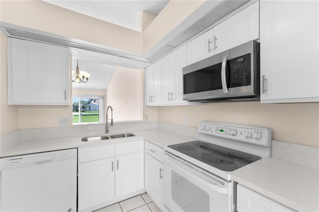 A kitchen with white cabinets, stainless steel appliances, and a pass-through window to the dining area — 1113 LUCAYA CIRCLE, ORLANDO, FL