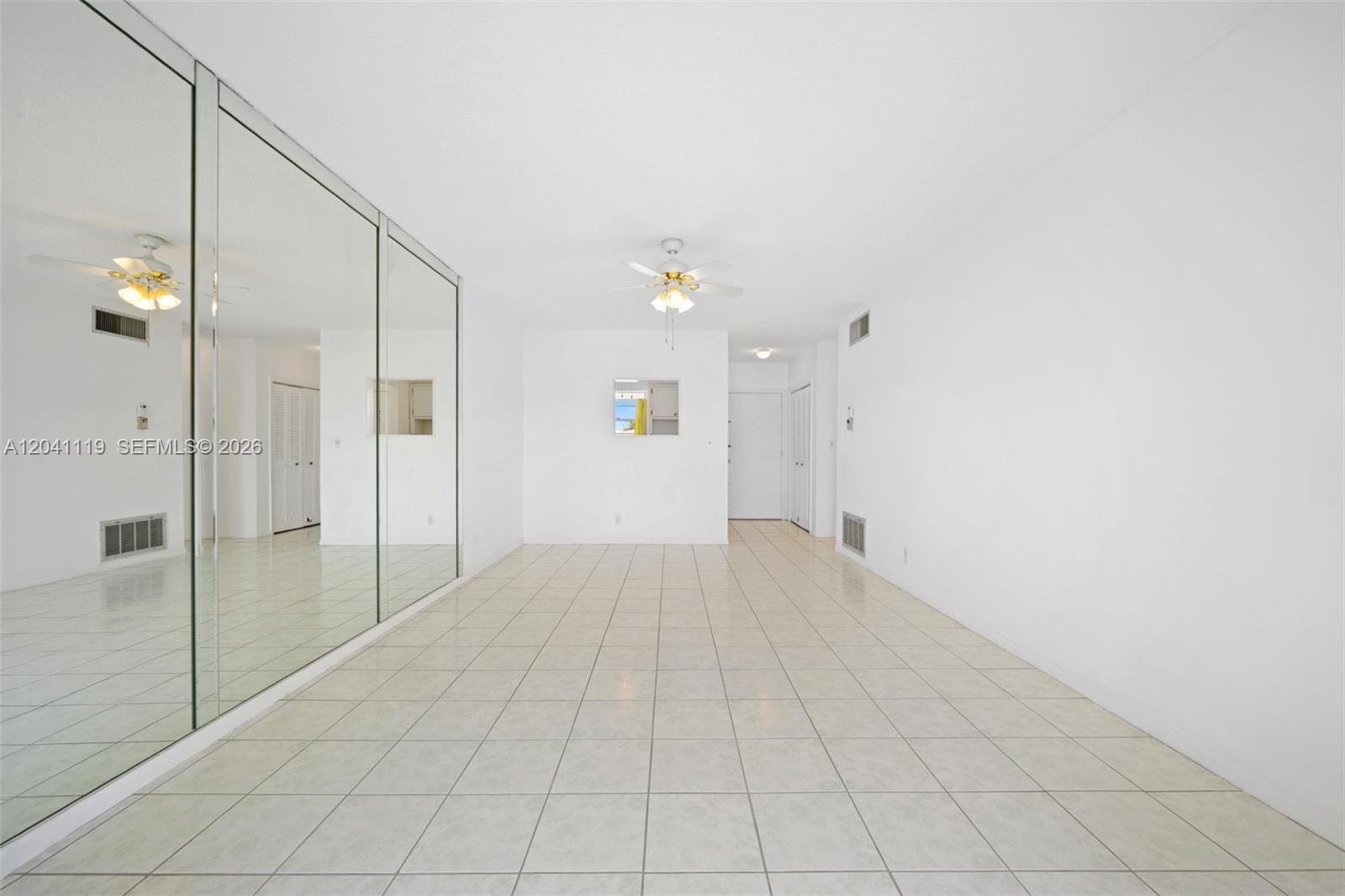 A bright, empty room features white walls, light-colored tile flooring, and a mirrored wall — 1116 Lake Ter # 208, Boynton Beach FL 33426, BOYNTON BEACH, FL