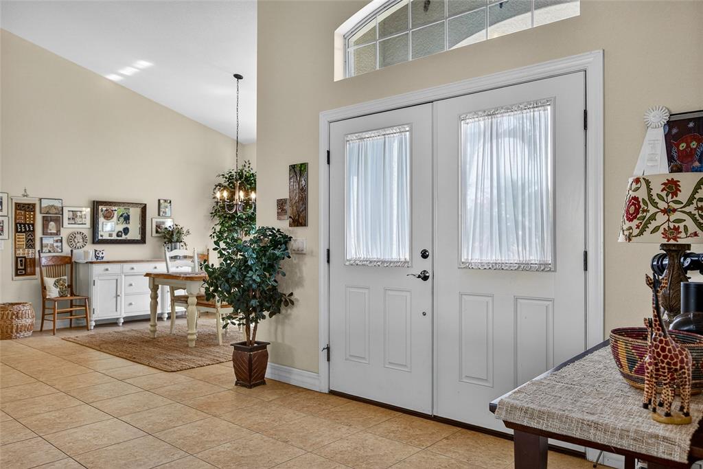 An entryway with tile floors leads to a dining area with a chandelier and double doors — 9353 BLUEGILL CIRCLE, PORT CHARLOTTE, FL