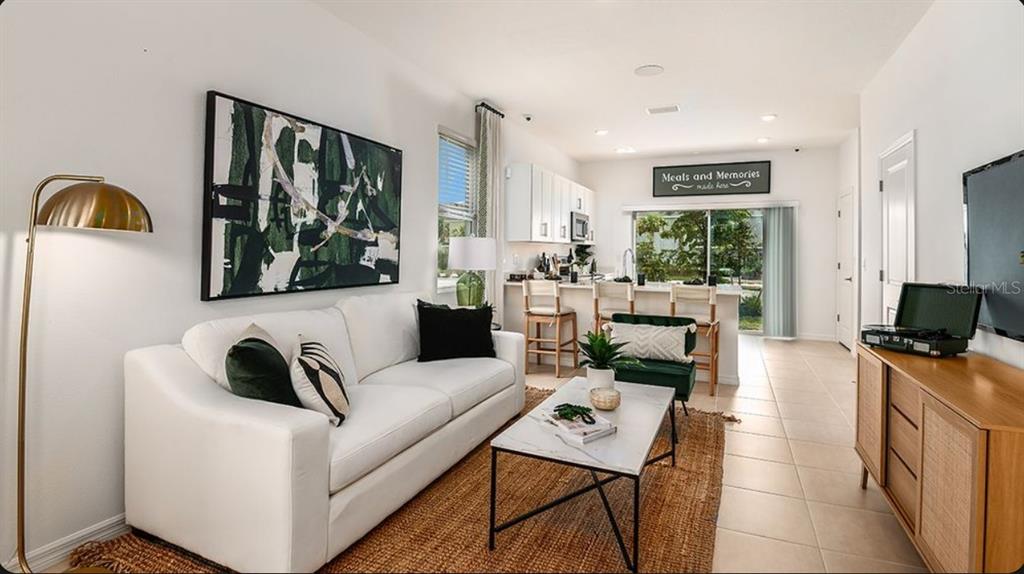 A living room with a white sofa, coffee table, and open kitchen with bar seating — 10656 ORBIT TERRACE, SARASOTA, FL