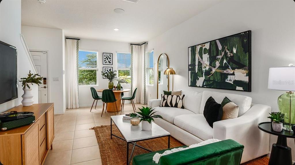 A bright living and dining area features a white sofa, marble coffee table, and green accents — 10656 ORBIT TERRACE, SARASOTA, FL
