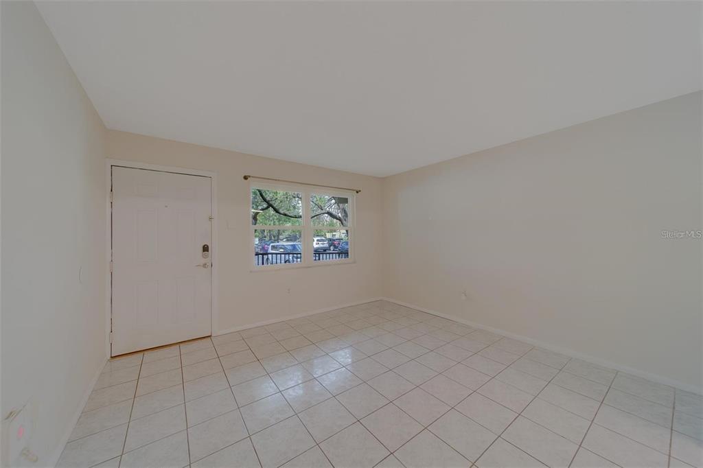 An empty room with white walls, a tiled floor, a white door, and a window — 2500 HARN BOULEVARD UNIT F12, CLEARWATER, FL