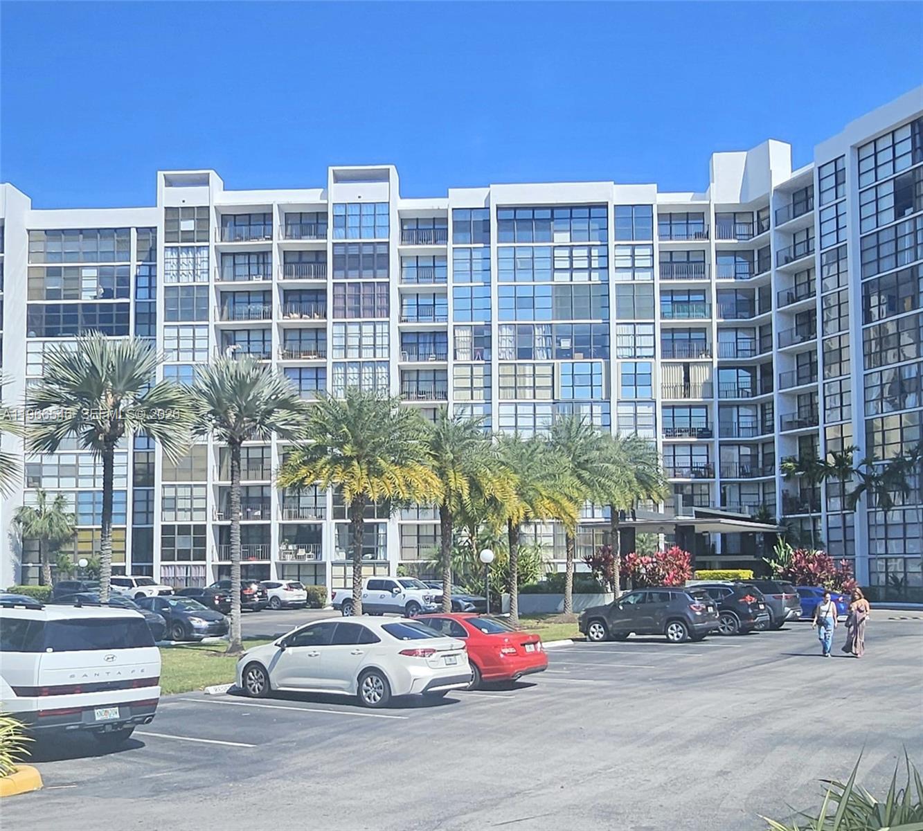 A multi-story apartment building with a parking lot and palm trees in the foreground — 1000 Parkview Dr # 605, Hallandale Beach FL 33009, HALLANDALE BEACH, FL
