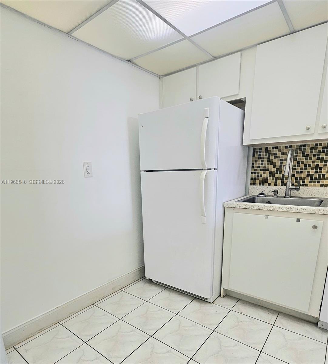 A small kitchen features a white refrigerator, white cabinets, a sink, and tiled flooring — 1000 Parkview Dr # 605, Hallandale Beach FL 33009, HALLANDALE BEACH, FL