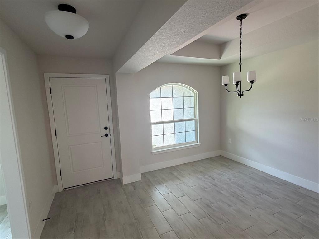 This dining area features light-colored wood-look tile flooring, a chandelier, and an arched window — 17532 ROBINSON AVENUE, PORT CHARLOTTE, FL