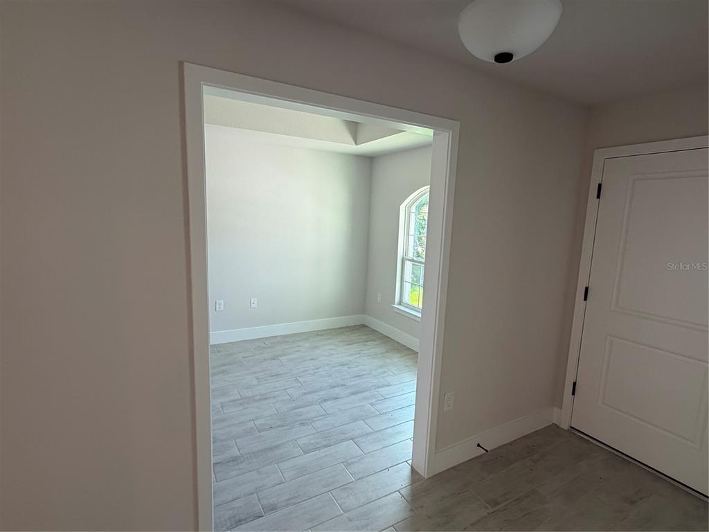 A view through a doorway into a room with light-colored tile flooring and arched windows — 17532 ROBINSON AVENUE, PORT CHARLOTTE, FL