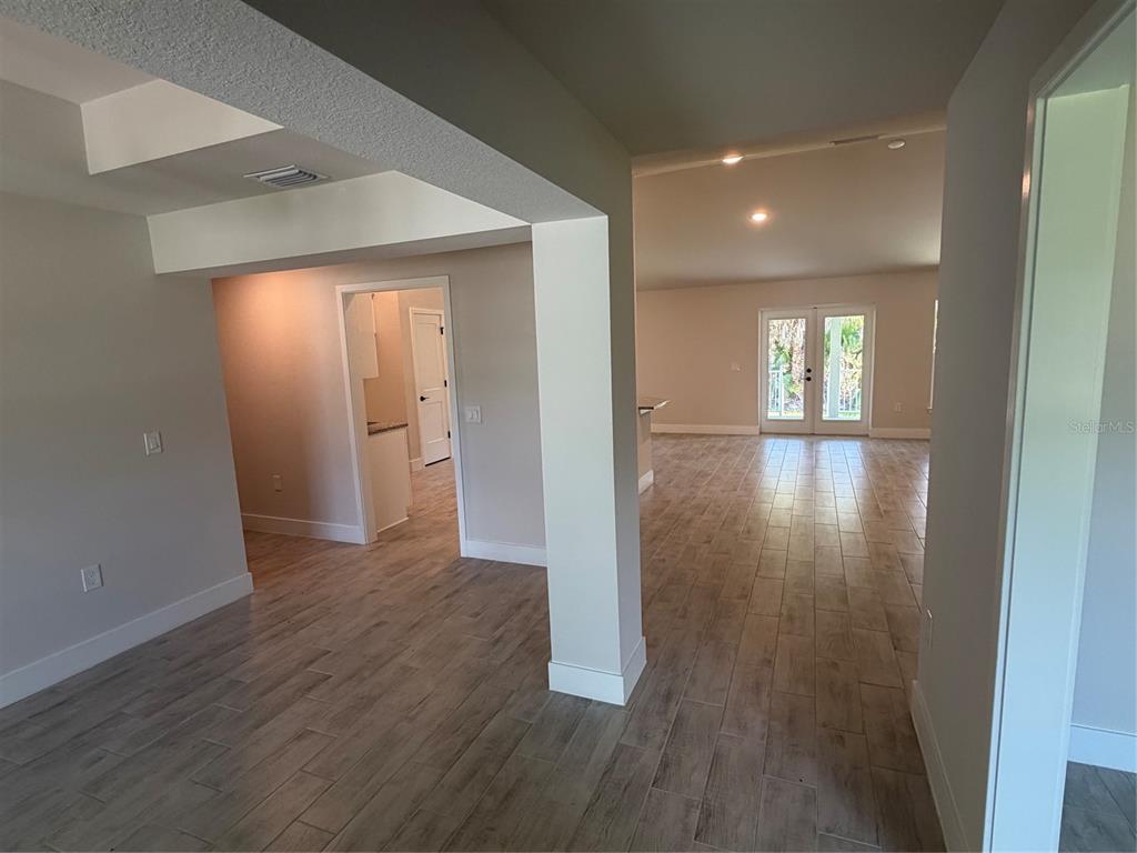 An open-concept living area features light wood-look tile flooring and a white support pillar — 17532 ROBINSON AVENUE, PORT CHARLOTTE, FL