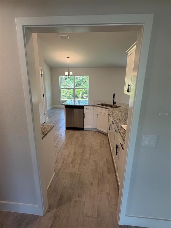 A kitchen with granite countertops, white cabinets, and wood-look tile flooring viewed through a doorway — 17532 ROBINSON AVENUE, PORT CHARLOTTE, FL