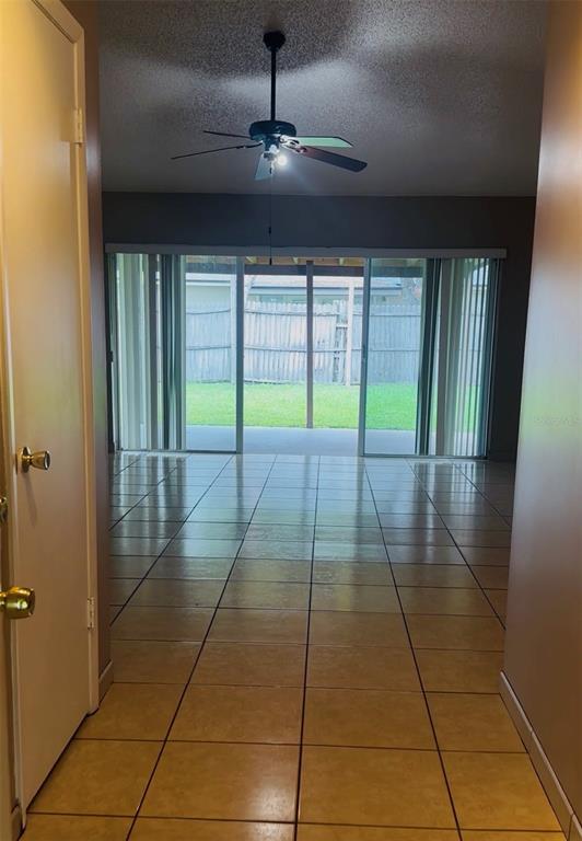 A view from a doorway looking into a tiled living area with a ceiling fan — 12123 AGANA STREET, ORLANDO, FL