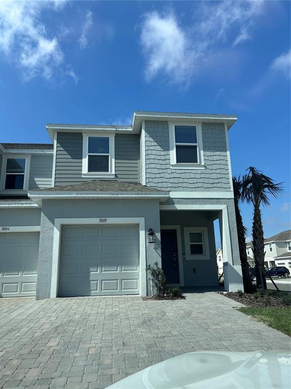 A two-story townhouse exterior features a gray garage, shingle siding, and a paved driveway — 3010 CANARY AVENUE, DAVENPORT, FL
