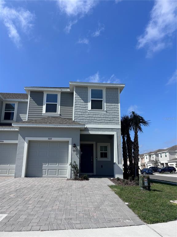 A two-story townhouse with a gray exterior, a single-car garage, and a paved driveway — 3010 CANARY AVENUE, DAVENPORT, FL