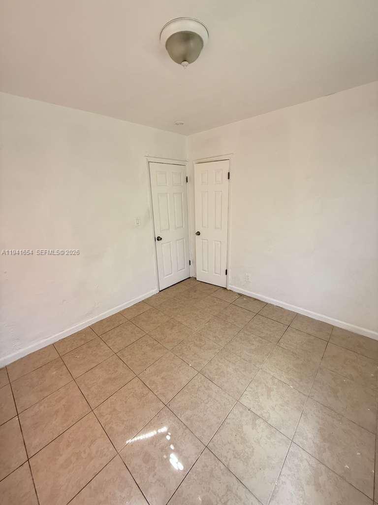 An empty room features white walls, tan tile flooring, and two closed white doors — 6720 NW 6th Ct # 6720, Miami FL 33150, MIAMI, FL