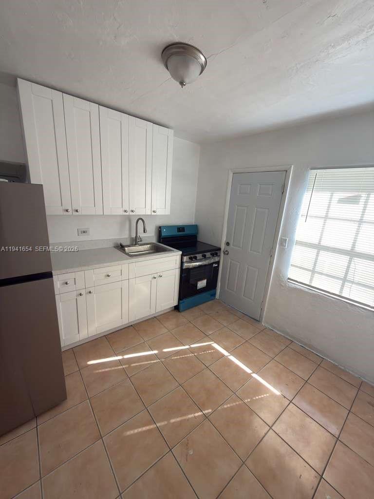 A kitchen features white cabinets, a stainless steel sink, a stove, and tiled flooring — 6720 NW 6th Ct # 6720, Miami FL 33150, MIAMI, FL