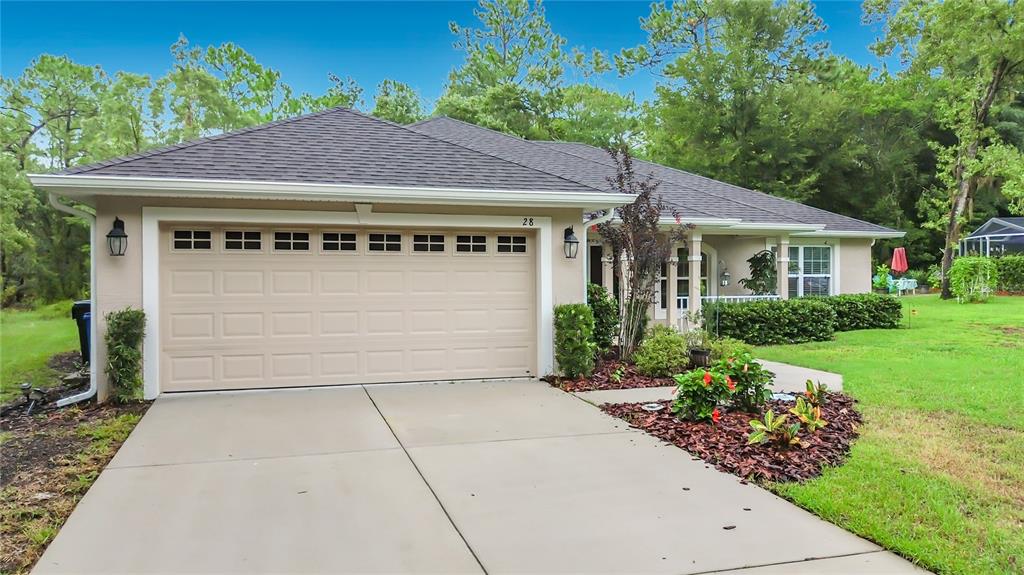 A single-story house with a beige garage door, a concrete driveway, and landscaped front yard — 28 HOLLY COURT, HOMOSASSA, FL