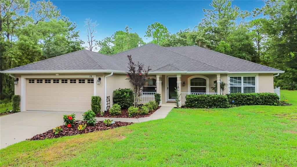 A single-story suburban house with a tan stucco exterior, a two-car garage, and landscaped yard — 28 HOLLY COURT, HOMOSASSA, FL