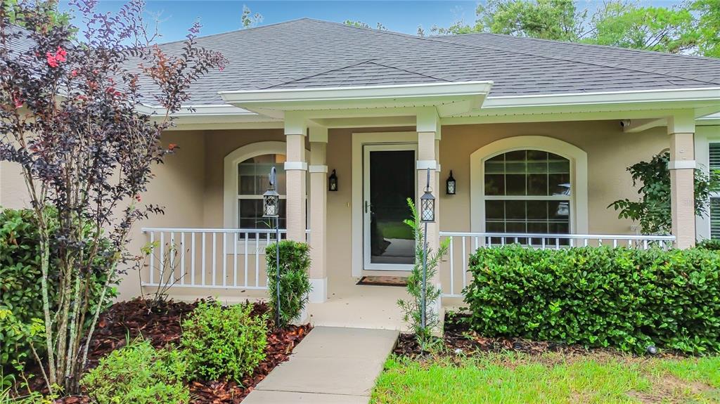 A front view of a house exterior featuring a covered porch, white railings, and landscaping — 28 HOLLY COURT, HOMOSASSA, FL