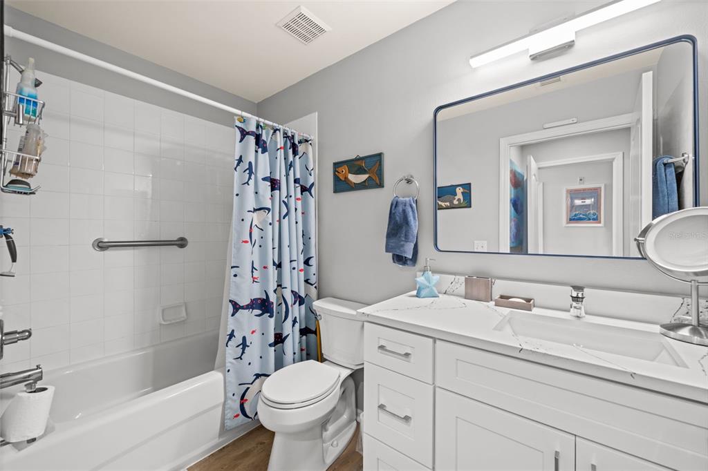 A hallway with light blue wainscoting and wood-look flooring leads toward an open living area — 10460 WASHINGTONIA PALM WAY UNIT 1342, FORT MYERS, FL