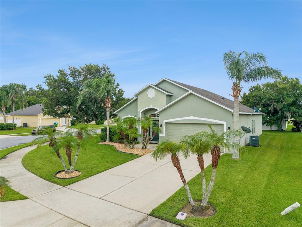 A light green single-story house with a two-car garage and palm trees in the yard — 327 MARATHON LANE, SANFORD, FL