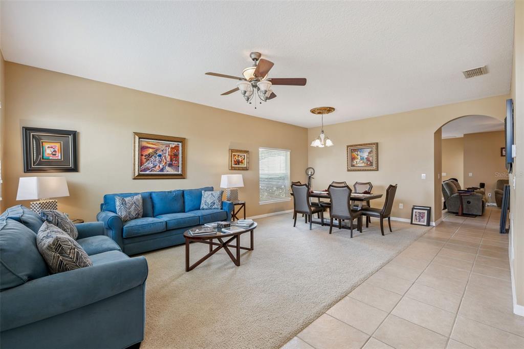 A living and dining area with blue sofas, a dining table, and beige carpet — 327 MARATHON LANE, SANFORD, FL