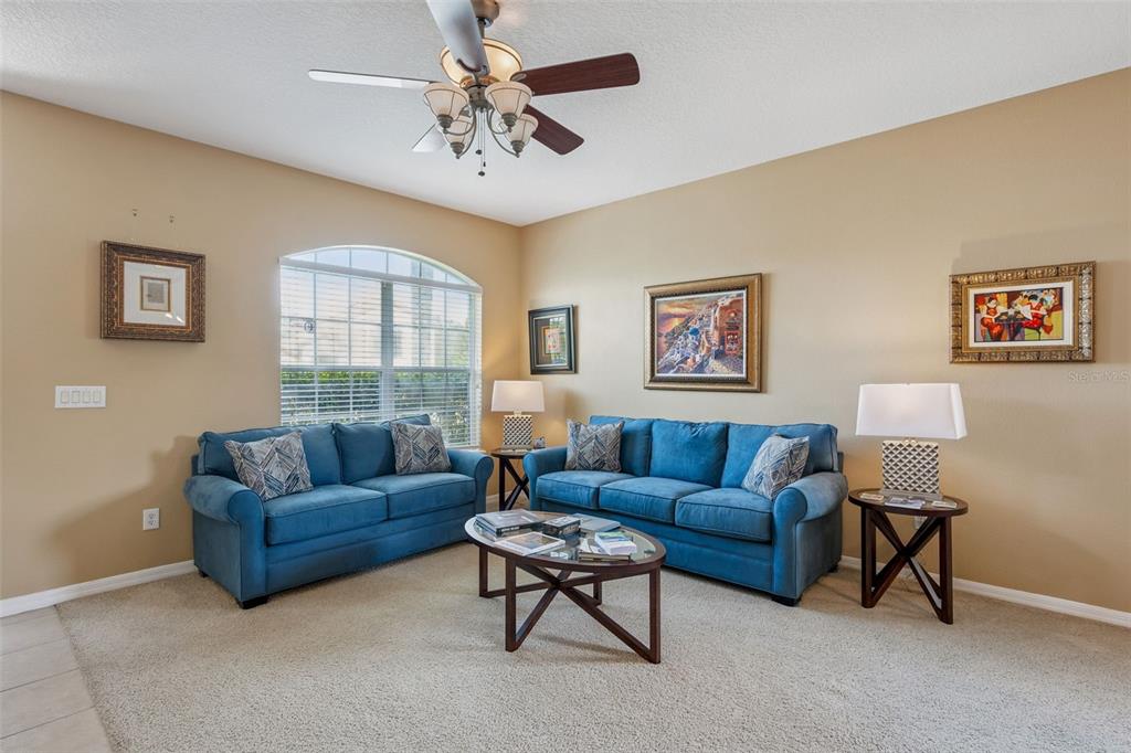 A living room features two blue sofas, a coffee table, and a ceiling fan — 327 MARATHON LANE, SANFORD, FL