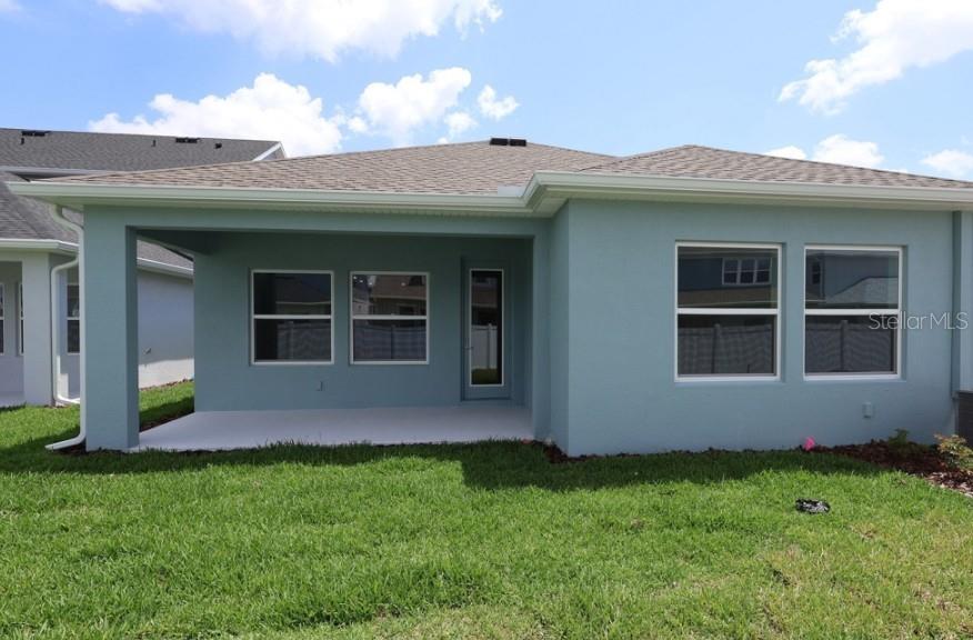 The exterior rear view of a light blue house features a covered patio and lawn — 634 KINGSWOOD COURT, BRADENTON, FL