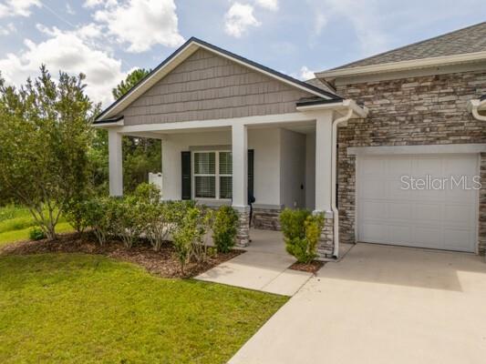 A single-story house exterior features a stone facade, a covered front porch, and a garage — 21 LANCELOT DRIVE, PALM COAST, FL