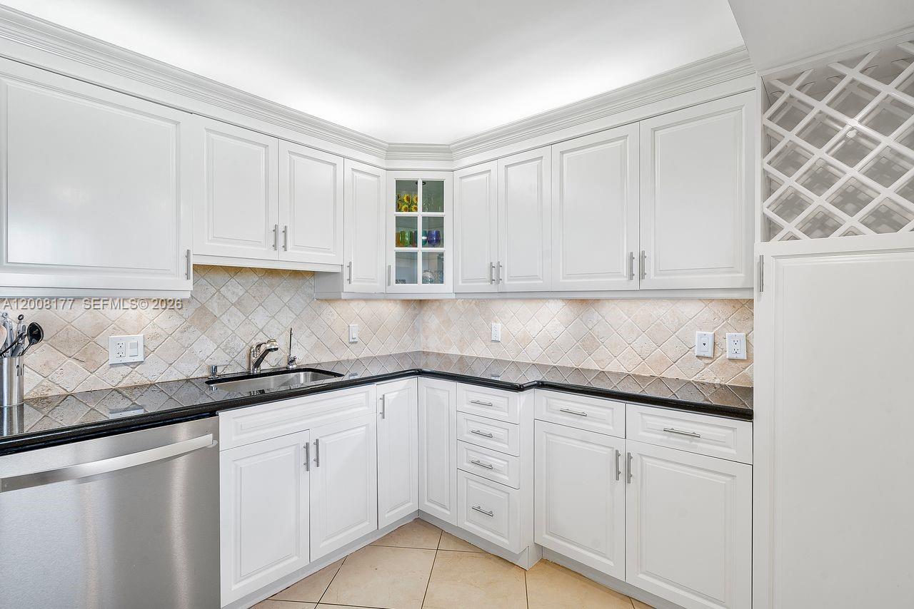 A kitchen features white cabinets, black countertops, and a tiled backsplash — 400 Ocean Trail Way # 302, Jupiter FL 33477, JUPITER, FL