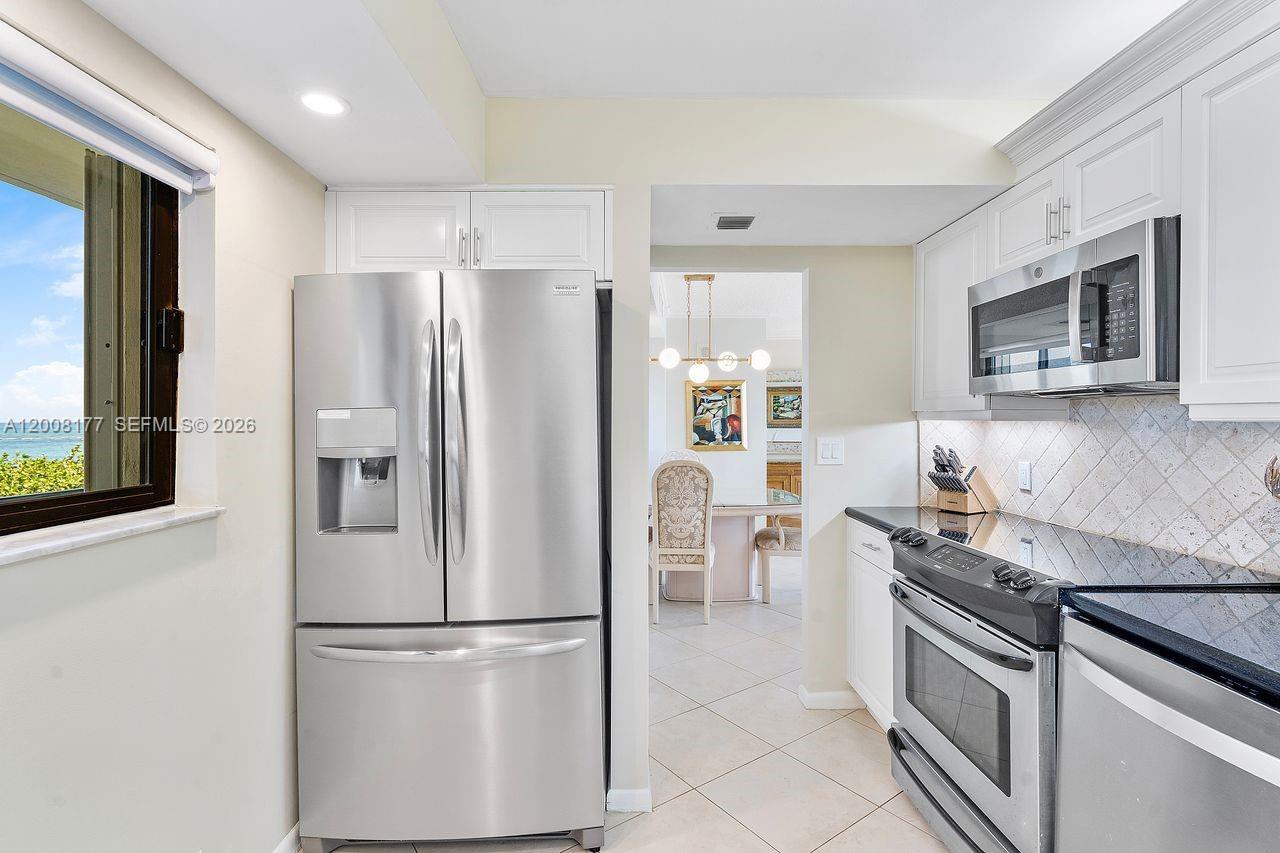 A kitchen features stainless steel appliances, white cabinetry, and a view of the ocean — 400 Ocean Trail Way # 302, Jupiter FL 33477, JUPITER, FL