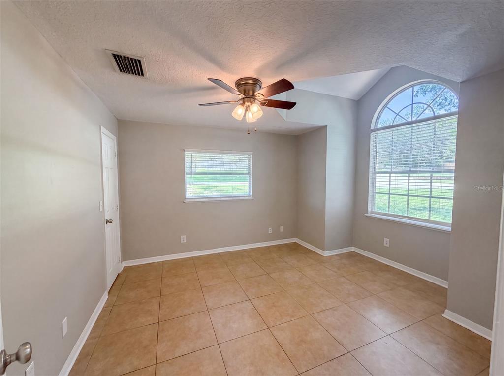 An empty room with tan tile flooring, a ceiling fan, and a large arched window — 17802 JEFFERSON STREET, WINTER GARDEN, FL