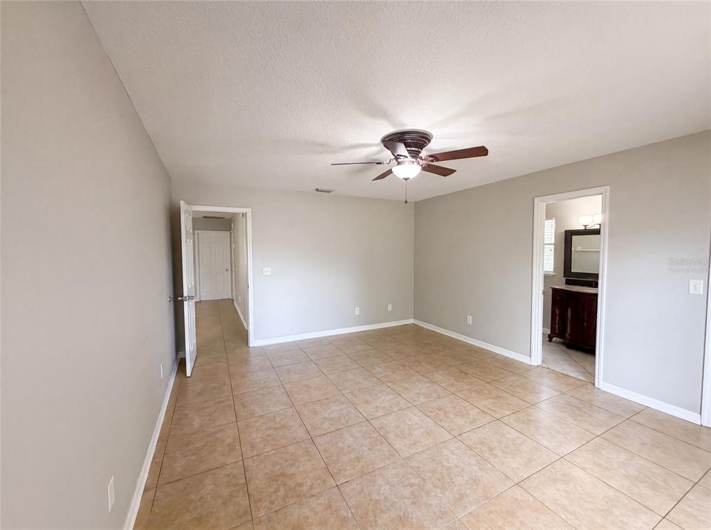 A room with beige walls, tile flooring, a ceiling fan, and two open doorways — 17802 JEFFERSON STREET, WINTER GARDEN, FL