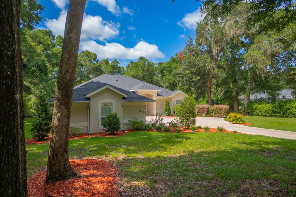 A single-story house with a gray roof and beige exterior sits on a grassy lot — 18976 SW 93RD LOOP, DUNNELLON, FL