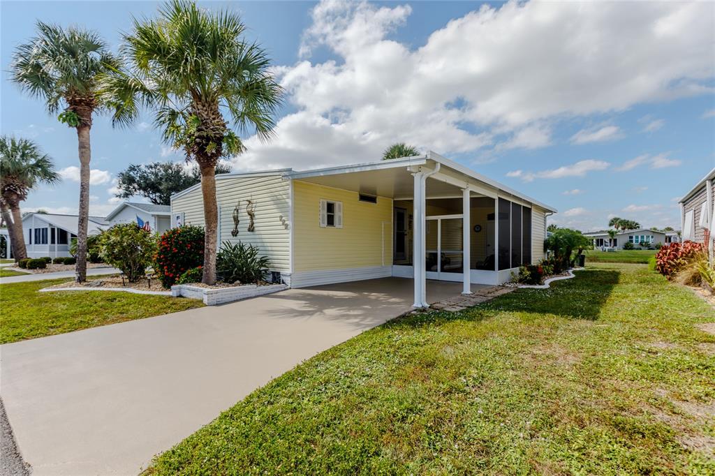 A yellow mobile home features a carport, a screened-in porch, and palm trees in front — 2100 KINGS HIGHWAY UNIT 283, PORT CHARLOTTE, FL