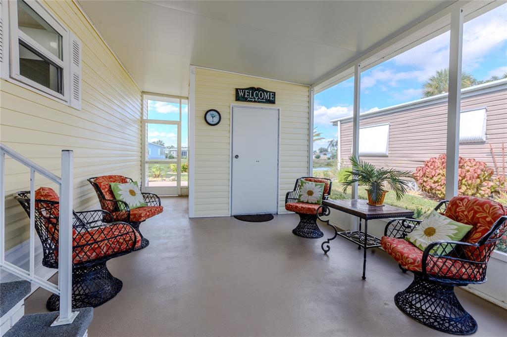 A screened-in porch features yellow siding, a white door, and four wicker chairs with cushions — 2100 KINGS HIGHWAY UNIT 283, PORT CHARLOTTE, FL