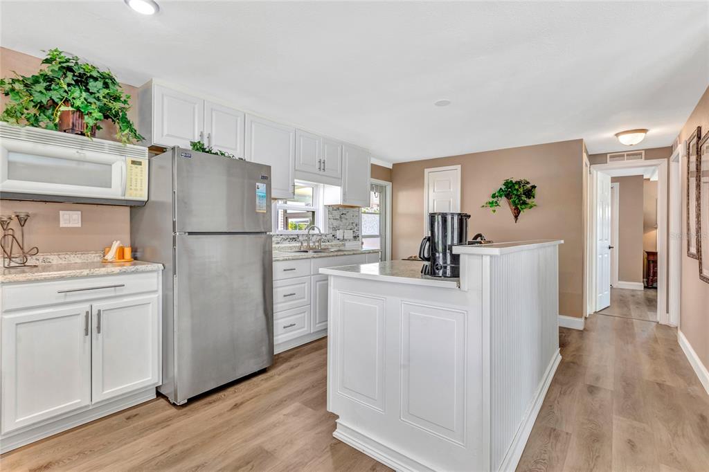 A kitchen features white cabinets, stainless steel appliances, and light wood-look flooring — 2100 KINGS HIGHWAY UNIT 283, PORT CHARLOTTE, FL